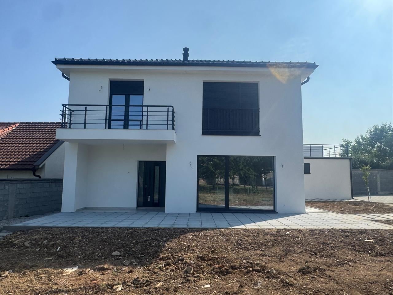 Shtëpi e bardhë me roletë antracit mbi dritaren e madhe